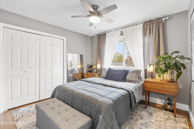 bedroom featuring a closet, baseboards, a ceiling fan, and wood finished floors
