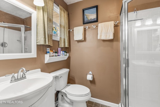 bathroom with baseboards, toilet, vanity, tile patterned floors, and a stall shower