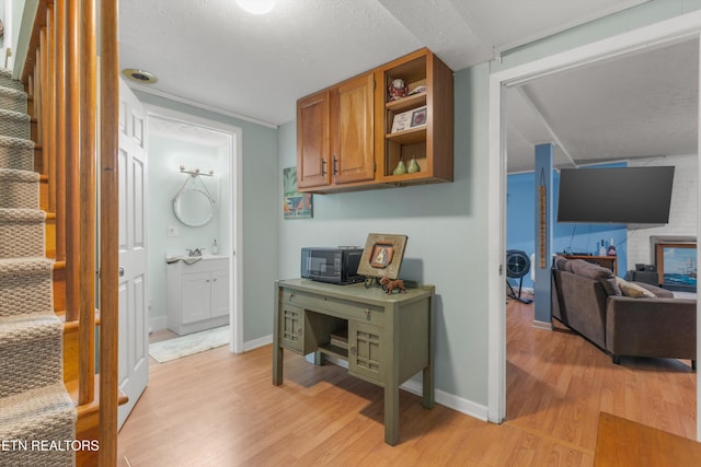 interior space featuring light wood-style floors, baseboards, a textured ceiling, and stairway