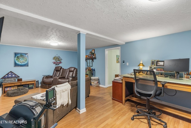 office area featuring a textured ceiling, baseboards, and wood finished floors