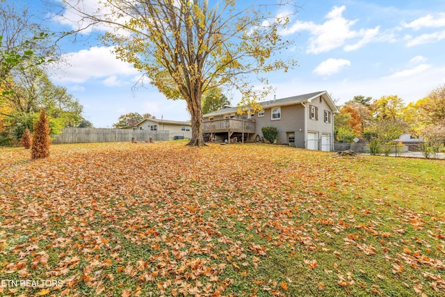 view of yard featuring an attached garage, a wooden deck, and fence