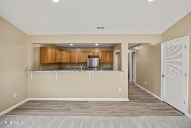 299 Shire Ln, Celina, TN 38551 - kitchen featuring a peninsula, freestanding refrigerator, baseboards, a kitchen breakfast bar, and light stone countertops