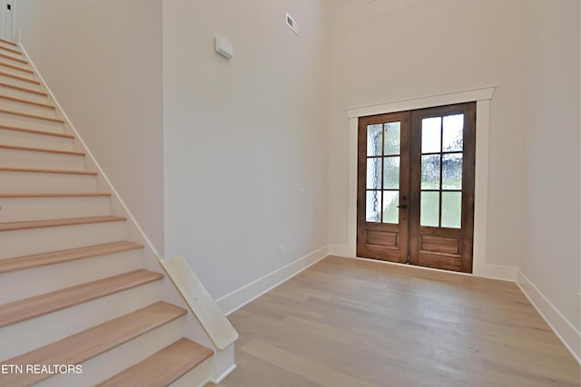 entrance foyer with stairway, french doors, wood finished floors, and baseboards
