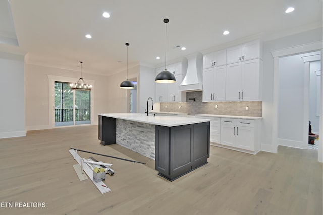 kitchen with custom range hood, backsplash, light countertops, baseboards, and light wood finished floors