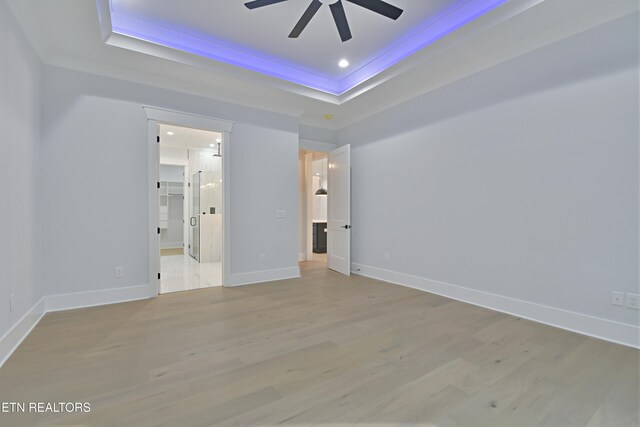 unfurnished bedroom featuring a tray ceiling, light wood-style floors, baseboards, and recessed lighting