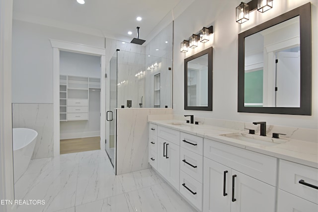 bathroom featuring a stall shower, marble finish flooring, a freestanding bath, double vanity, and a spacious closet