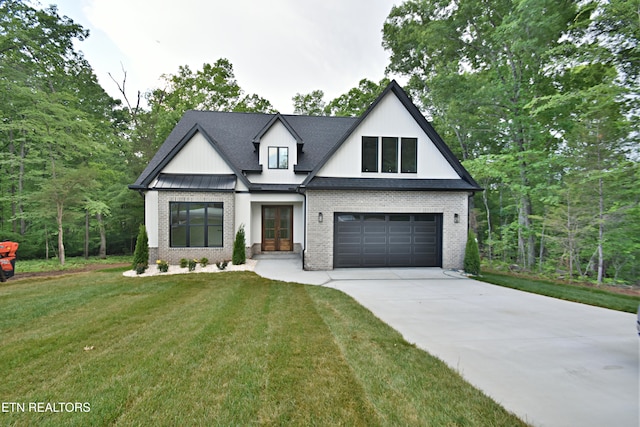 modern farmhouse style home featuring driveway, brick siding, a front yard, french doors, and a garage