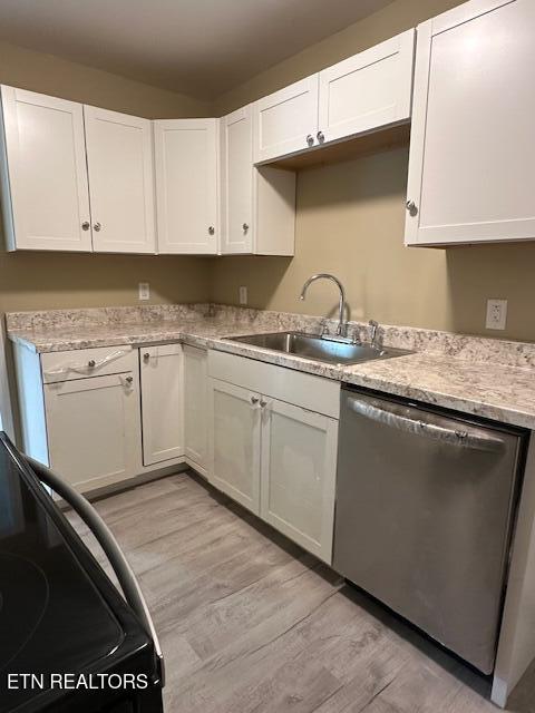 kitchen with a sink, light wood finished floors, dishwasher, and white cabinets