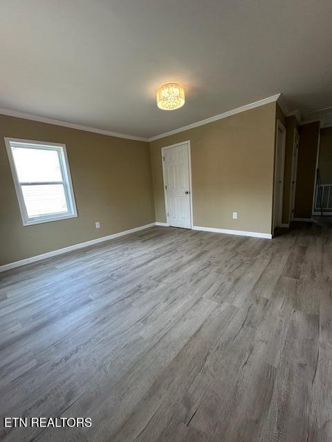 spare room with baseboards, ornamental molding, and wood finished floors