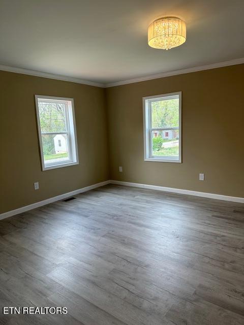 unfurnished room featuring crown molding, baseboards, visible vents, and wood finished floors