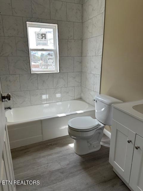 bathroom with toilet, bathtub / shower combination, wood finished floors, and vanity