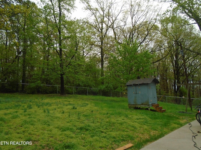 view of yard with a storage shed, a fenced backyard, and an outbuilding