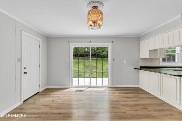 unfurnished dining area with a chandelier, light wood-style floors, visible vents, and crown molding
