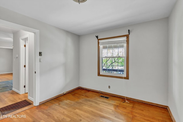 unfurnished room with baseboards, visible vents, and light wood-type flooring
