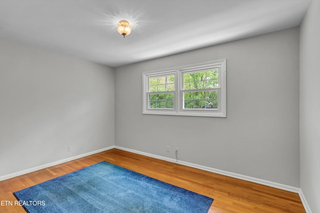 spare room featuring baseboards and wood finished floors