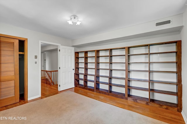 unfurnished bedroom with baseboards, wood finished floors, and visible vents