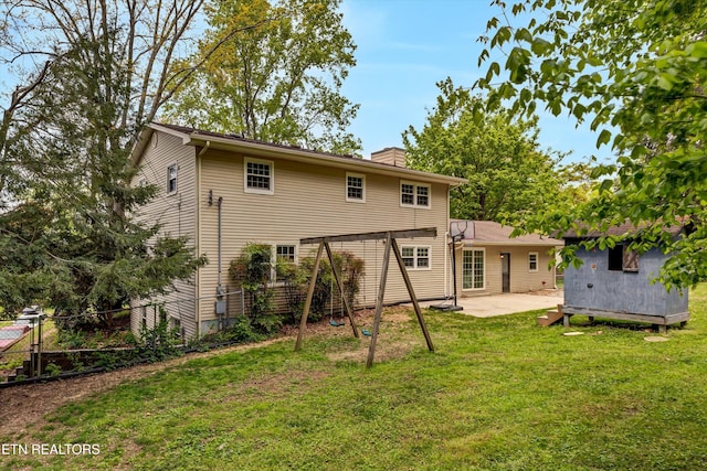 rear view of house with a chimney, fence, an outdoor structure, a patio, and a lawn