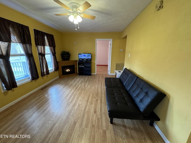 sitting room featuring baseboards, ceiling fan, visible vents, and wood finished floors