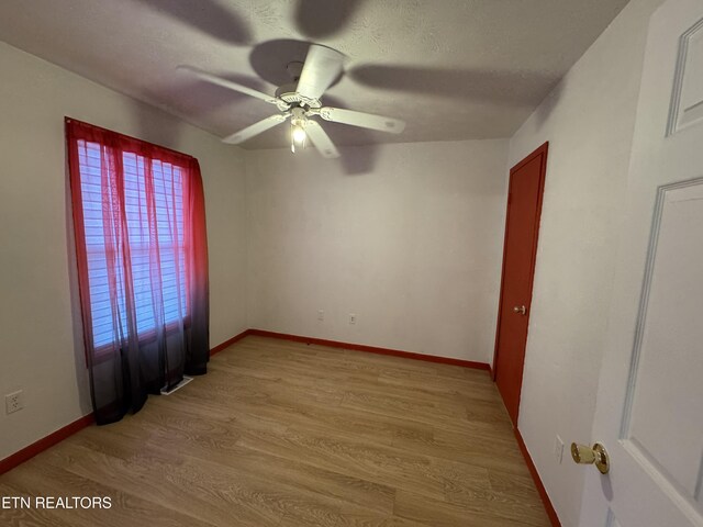 unfurnished room featuring baseboards, light wood-style flooring, ceiling fan, and a textured ceiling