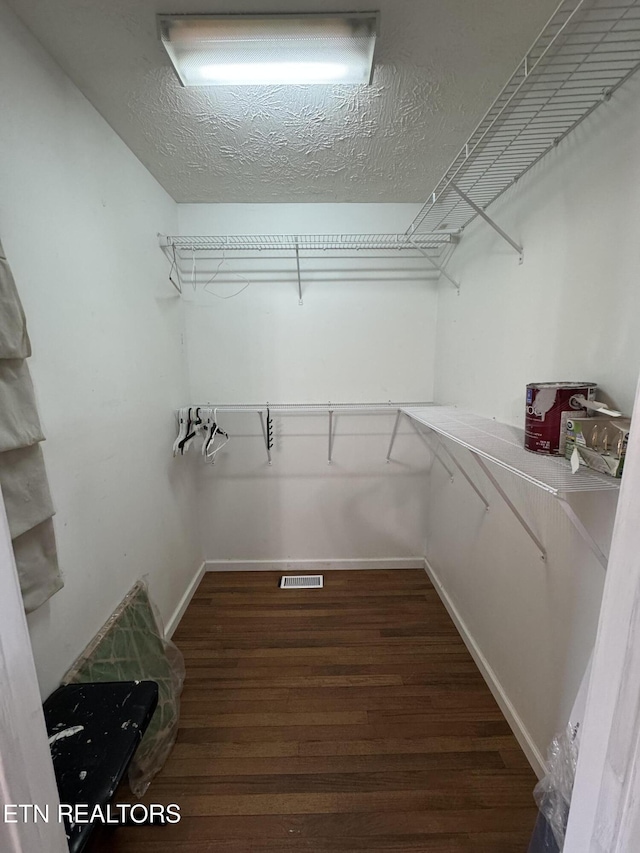 walk in closet with visible vents and dark wood-style flooring