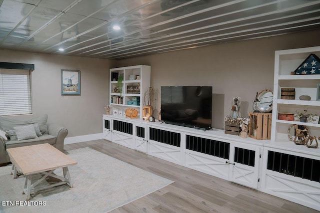living area with baseboards and wood finished floors