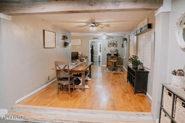 dining space featuring light wood finished floors, a ceiling fan, and baseboards