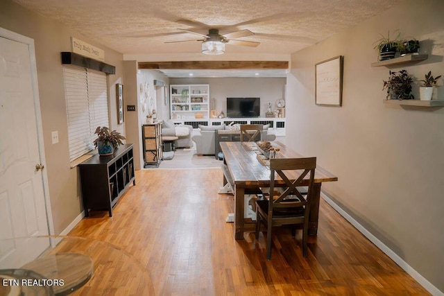 dining room featuring a ceiling fan, baseboards, a textured ceiling, and light wood-style floors