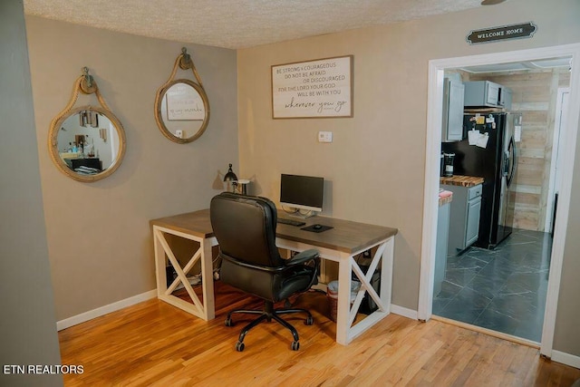 office featuring baseboards, wood finished floors, and a textured ceiling