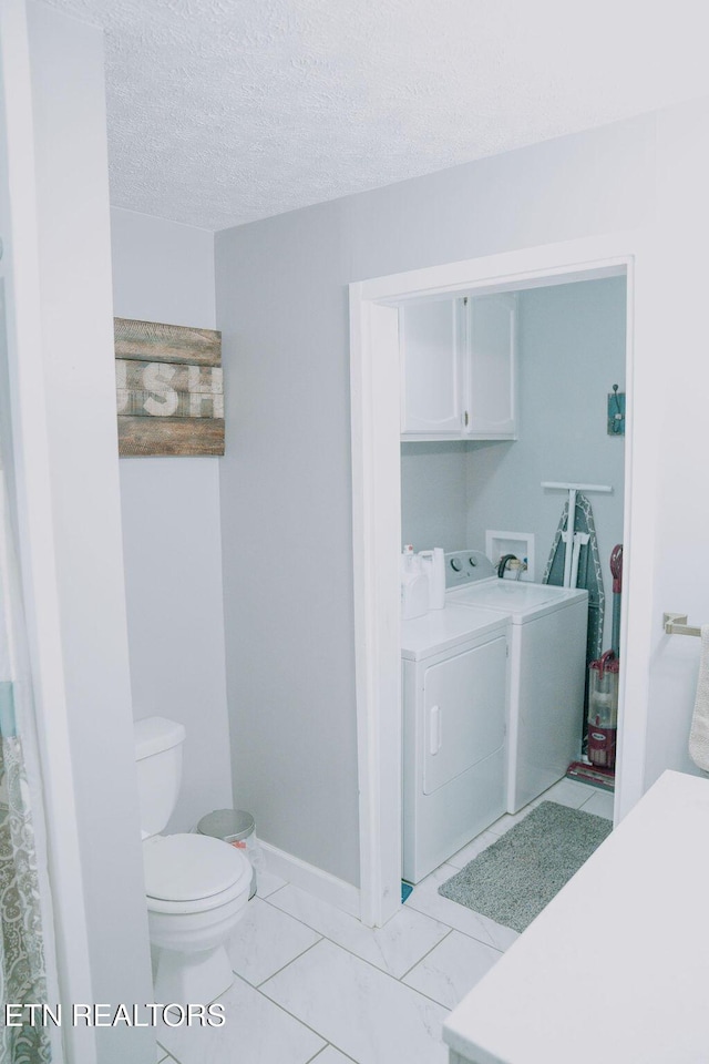 bathroom with a textured ceiling, toilet, baseboards, and separate washer and dryer