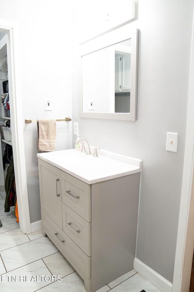 bathroom featuring baseboards, marble finish floor, and vanity