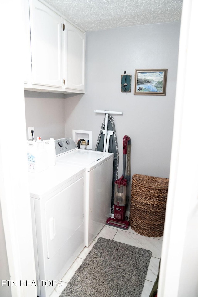 washroom featuring washing machine and dryer, a textured ceiling, and cabinet space