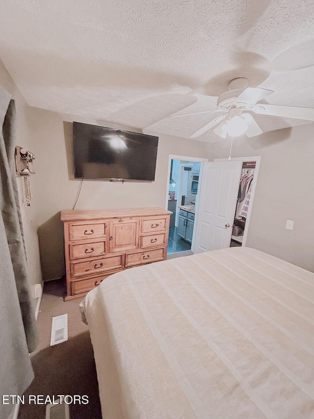 bedroom with ensuite bath, a ceiling fan, and a textured ceiling