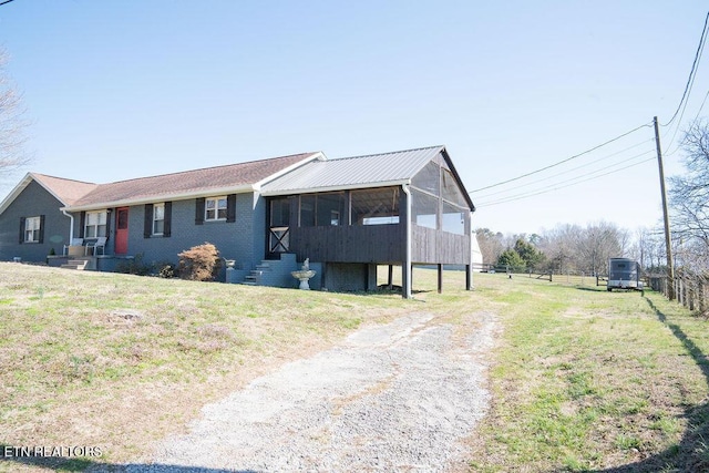 single story home featuring a front lawn, a sunroom, fence, and dirt driveway