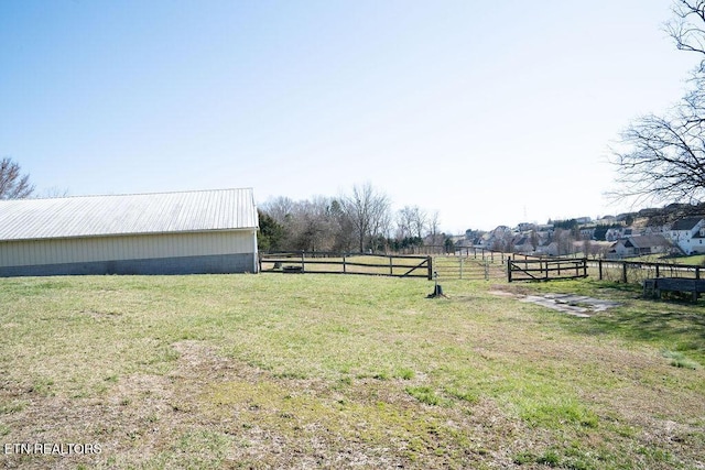 view of yard featuring fence, a rural view, an outdoor structure, and a pole building