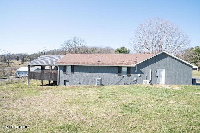 rear view of property with brick siding, a lawn, and fence