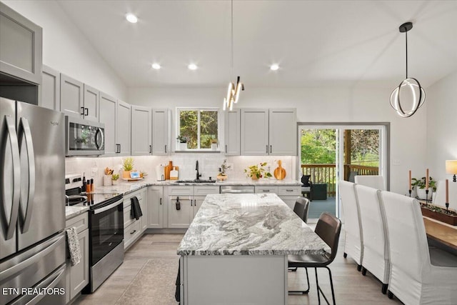 kitchen with a sink, a breakfast bar area, decorative backsplash, and appliances with stainless steel finishes
