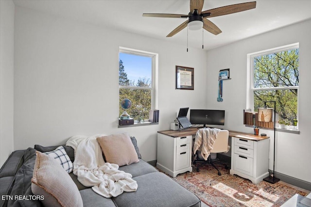 office space featuring baseboards, ceiling fan, and a healthy amount of sunlight