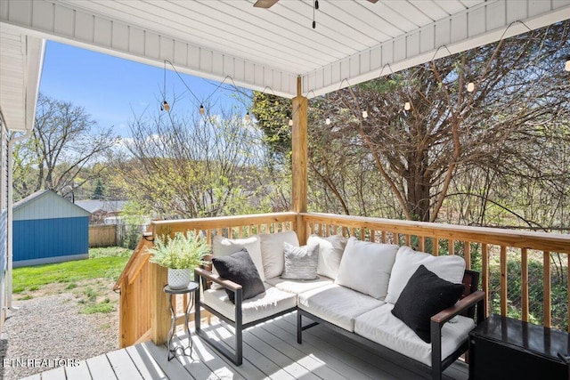 deck featuring fence, an outdoor structure, outdoor lounge area, a storage unit, and ceiling fan