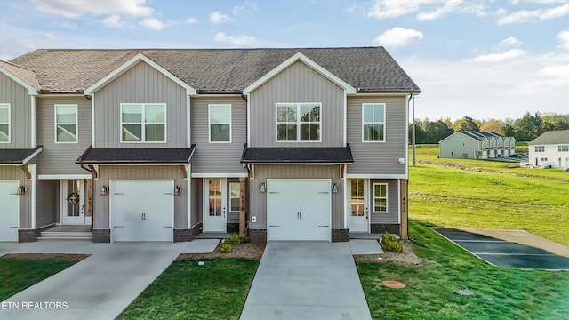 multi unit property with board and batten siding, a shingled roof, a front yard, and concrete driveway