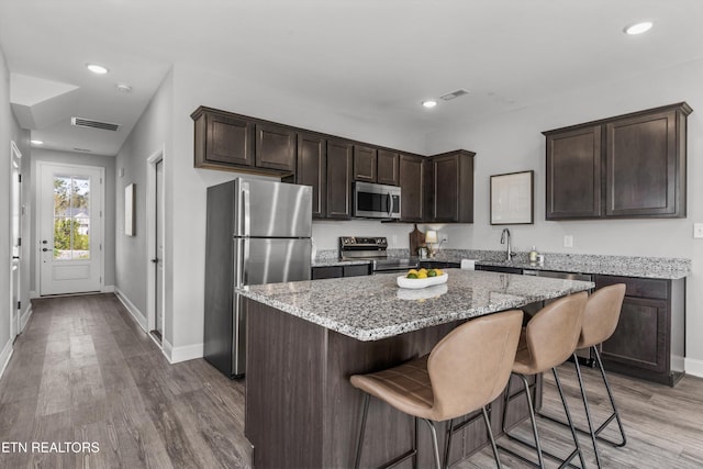 kitchen with a center island, dark brown cabinets, baseboards, appliances with stainless steel finishes, and visible vents