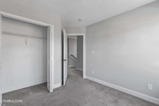 unfurnished bedroom with baseboards, carpet flooring, and a closet