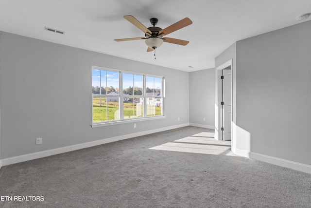 carpeted spare room featuring baseboards, a ceiling fan, and visible vents