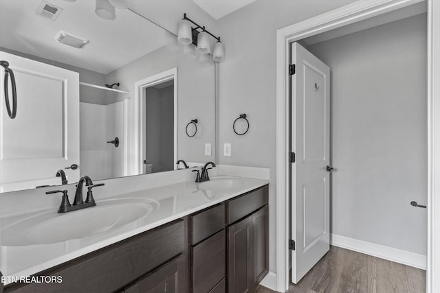 full bath featuring wood finished floors, visible vents, a sink, and double vanity