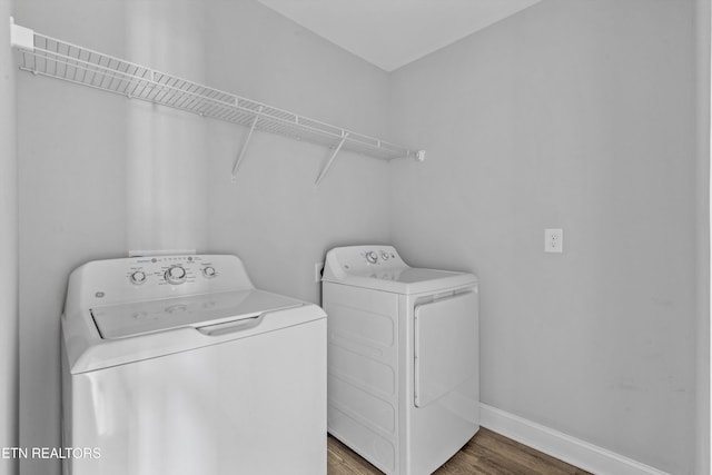 washroom with wood finished floors, washing machine and clothes dryer, baseboards, and laundry area