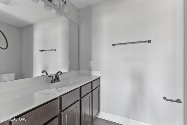 bathroom with baseboards, toilet, vanity, and wood finished floors