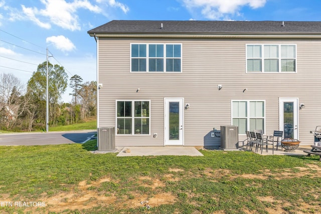 rear view of property with a patio area, a lawn, a fire pit, and central AC