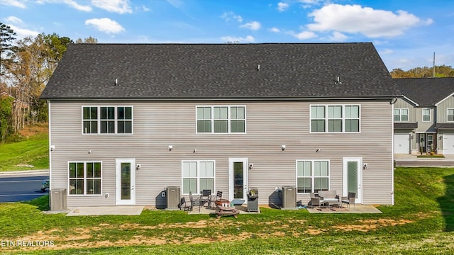back of property featuring a yard, a patio area, and roof with shingles
