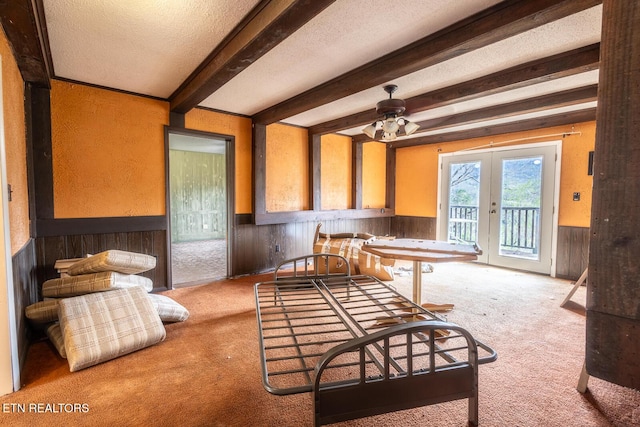 kitchen featuring carpet floors, beamed ceiling, wood walls, and wainscoting