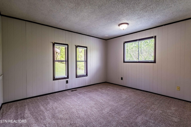 unfurnished room with carpet flooring, a textured ceiling, and visible vents