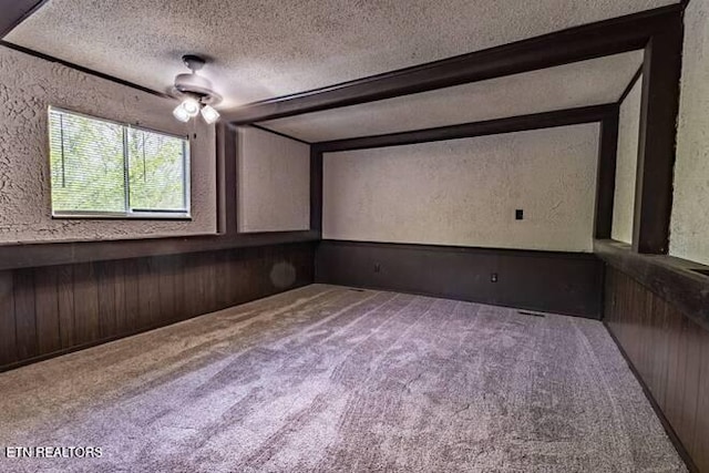 carpeted home theater room featuring wooden walls, a textured wall, and a textured ceiling